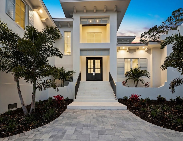 entrance to property featuring french doors and stucco siding