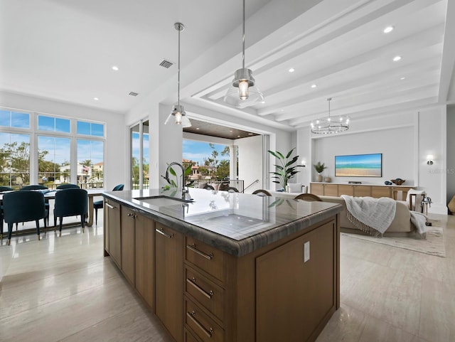 kitchen with a sink, dark countertops, a center island with sink, recessed lighting, and a chandelier