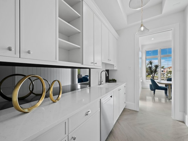 bar featuring a sink, dishwasher, baseboards, pendant lighting, and a raised ceiling