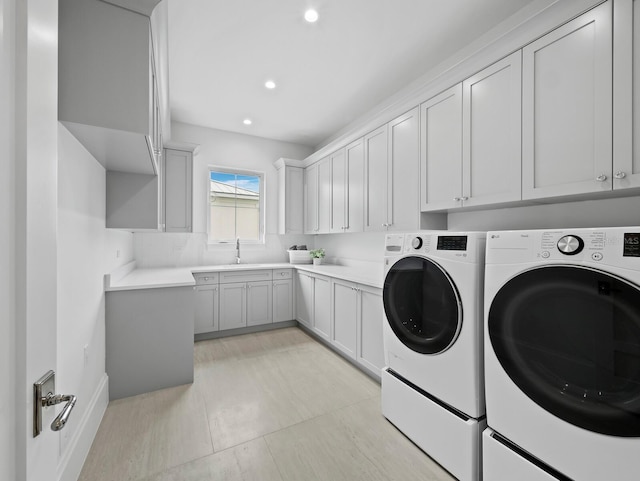 washroom featuring washing machine and clothes dryer, cabinet space, and recessed lighting
