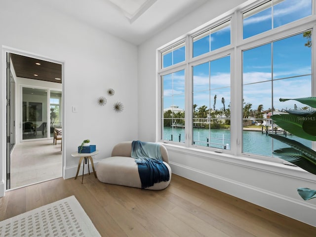 living area with baseboards, a water view, wood finished floors, and healthy amount of natural light