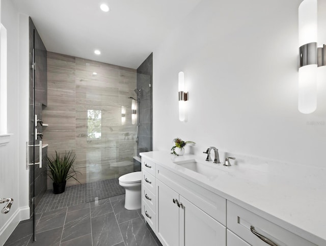 bathroom with tiled shower, toilet, recessed lighting, vanity, and marble look tiles