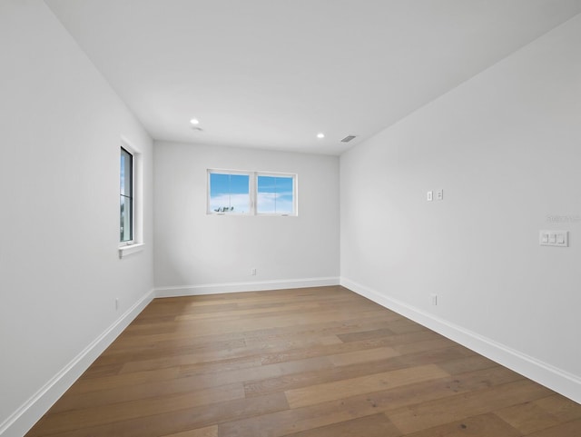 unfurnished room featuring wood finished floors, baseboards, and recessed lighting
