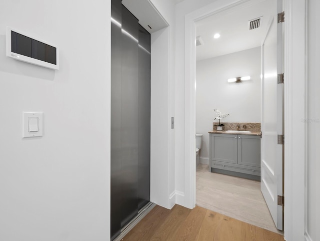 bathroom with wood finished floors, toilet, vanity, and baseboards