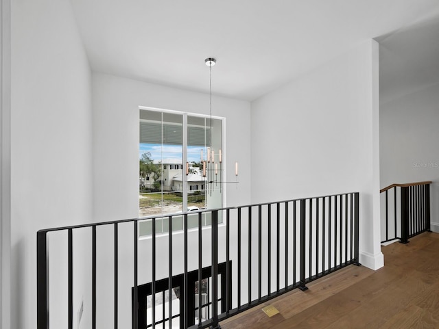 hall with an upstairs landing, wood finished floors, and baseboards