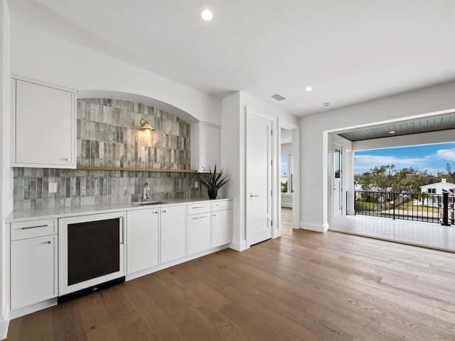 indoor wet bar with wine cooler, decorative backsplash, recessed lighting, dark wood-style floors, and baseboards