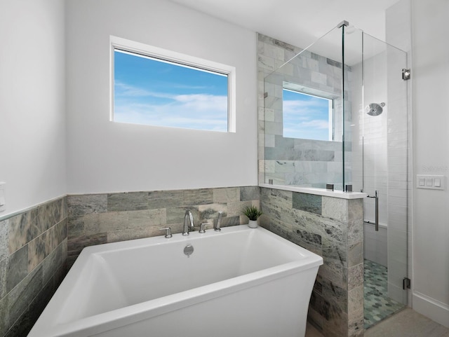 bathroom featuring a shower stall, a soaking tub, and tile walls