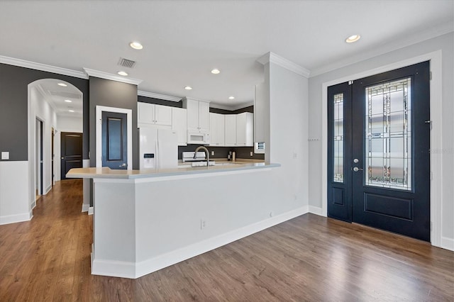 kitchen featuring a wealth of natural light, wood-type flooring, white cabinetry, and white appliances