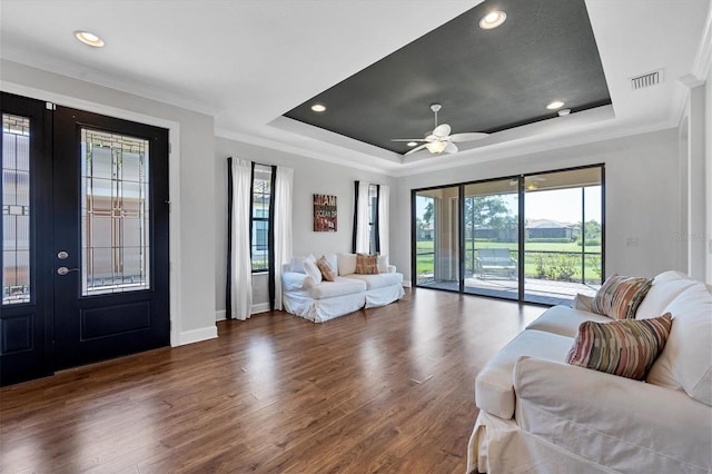 living room featuring a raised ceiling, ceiling fan, and dark hardwood / wood-style floors