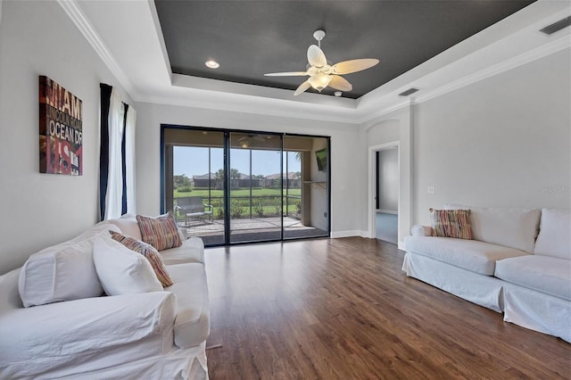 living room featuring ceiling fan, dark hardwood / wood-style flooring, ornamental molding, and a tray ceiling