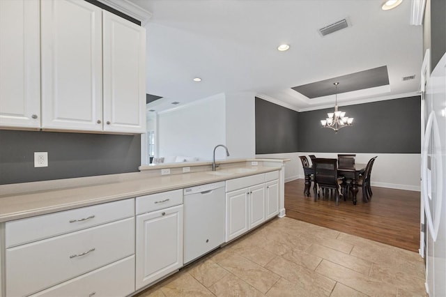 kitchen with white cabinets, sink, dishwasher, light tile floors, and a raised ceiling