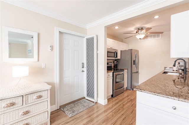 kitchen featuring light hardwood / wood-style flooring, ceiling fan, white cabinetry, appliances with stainless steel finishes, and sink