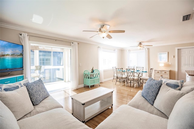 living room with ceiling fan, a healthy amount of sunlight, light wood-type flooring, and ornamental molding