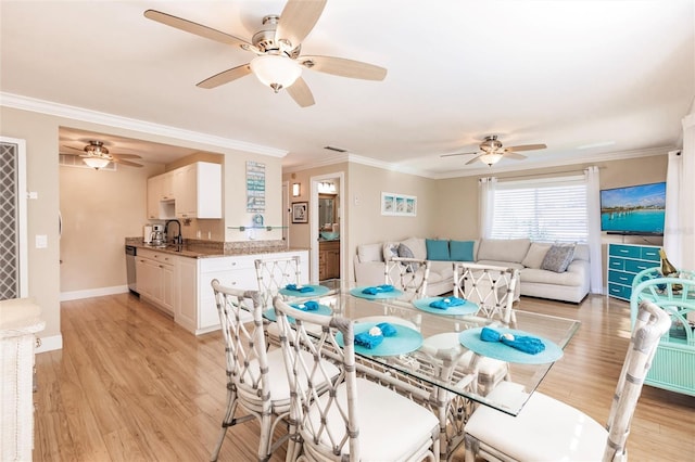 dining space with ceiling fan, light hardwood / wood-style floors, crown molding, and sink