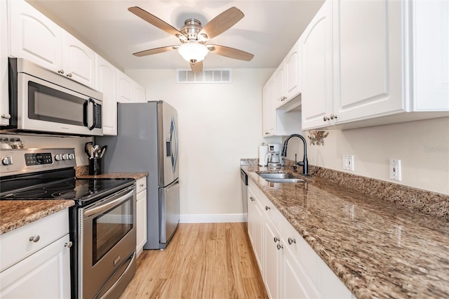 kitchen featuring light wood-type flooring, stainless steel appliances, white cabinets, sink, and ceiling fan