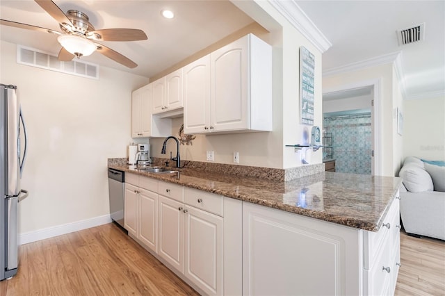 kitchen featuring white cabinetry, light wood-type flooring, appliances with stainless steel finishes, dark stone counters, and ceiling fan