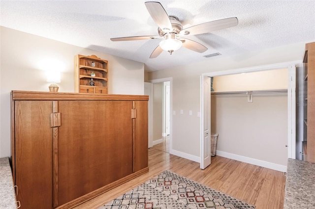 bedroom featuring a textured ceiling, a closet, ceiling fan, and light hardwood / wood-style flooring