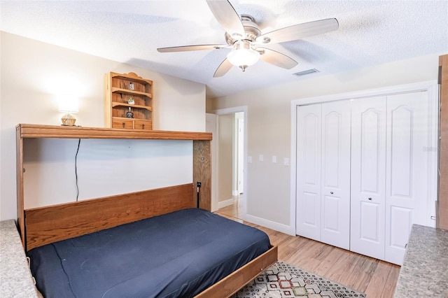 bedroom featuring a closet, ceiling fan, light hardwood / wood-style flooring, and a textured ceiling