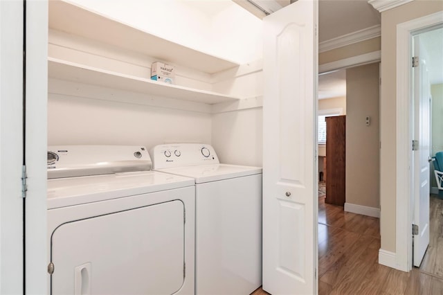 clothes washing area featuring crown molding, washer and dryer, and hardwood / wood-style floors