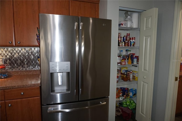 kitchen featuring tasteful backsplash, stainless steel fridge with ice dispenser, and dark stone counters