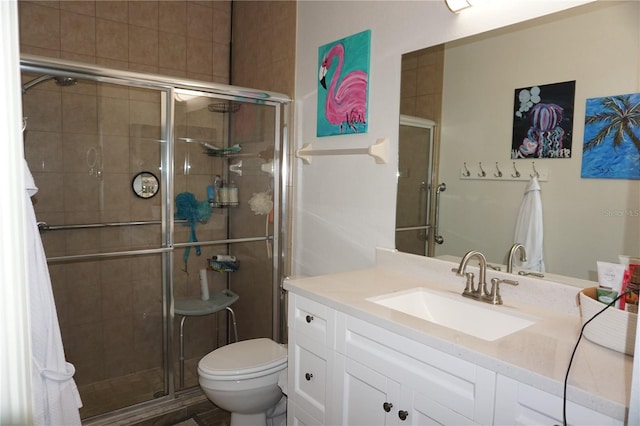 bathroom with a shower with door, vanity, and toilet