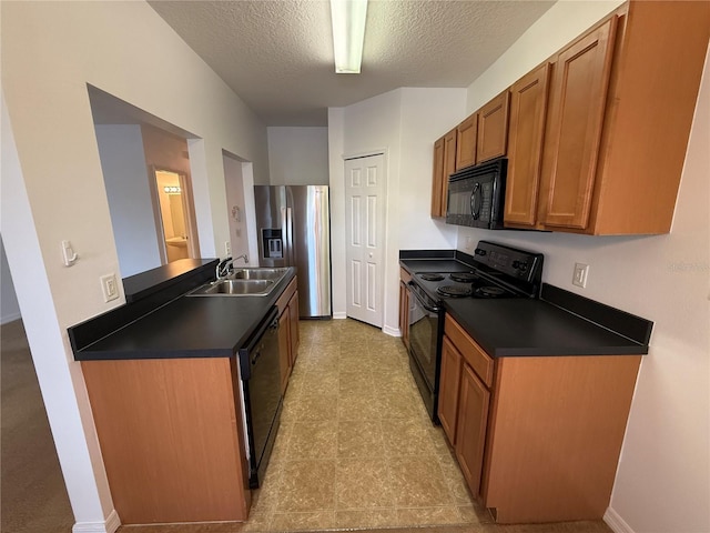 kitchen with a sink, dark countertops, black appliances, and a textured ceiling