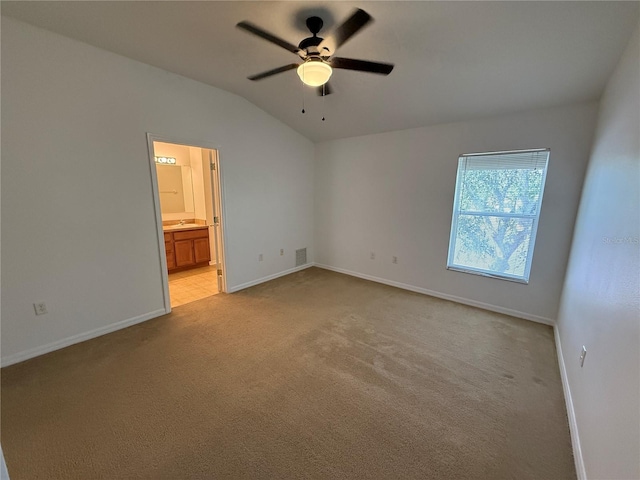 unfurnished bedroom with connected bathroom, light colored carpet, baseboards, vaulted ceiling, and visible vents