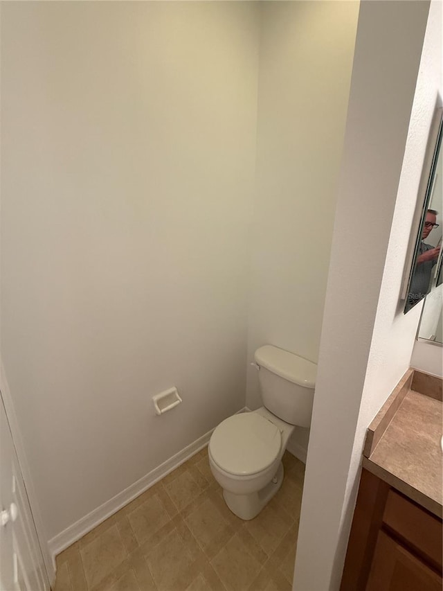 bathroom with baseboards, vanity, and toilet