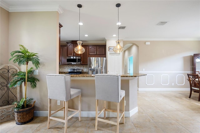 kitchen with pendant lighting, dark brown cabinetry, stainless steel appliances, and light stone counters