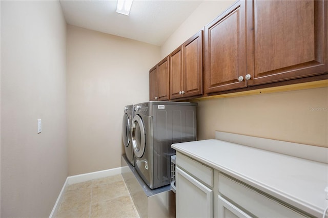 clothes washing area with washer and dryer, light tile patterned flooring, and cabinets