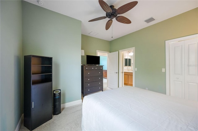 bedroom with a closet, light colored carpet, ceiling fan, and connected bathroom