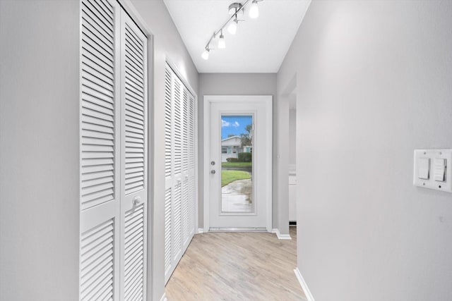 doorway to outside with light hardwood / wood-style flooring and track lighting