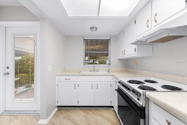 kitchen with plenty of natural light, white cabinets, electric range, and sink