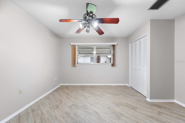 unfurnished bedroom featuring ceiling fan, light wood-type flooring, and a closet