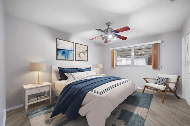 bedroom featuring light wood-type flooring, a textured ceiling, ceiling fan, and a closet