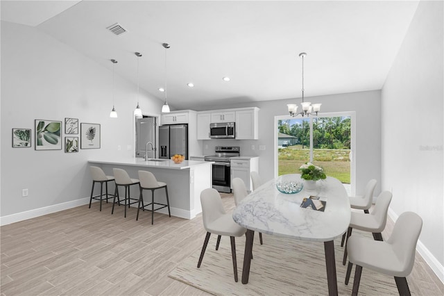 dining room featuring light hardwood / wood-style floors, sink, high vaulted ceiling, and a notable chandelier