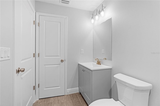 bathroom with wood-type flooring, vanity, and toilet