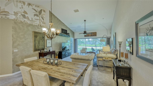 dining room with high vaulted ceiling, ceiling fan with notable chandelier, and carpet floors