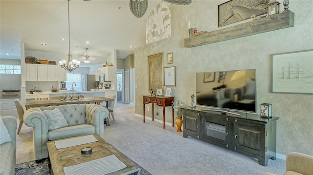 carpeted living room featuring sink, plenty of natural light, and ceiling fan with notable chandelier