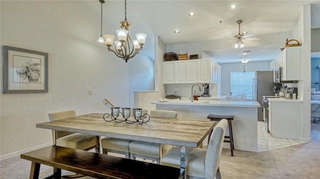 dining area featuring light carpet, sink, and ceiling fan with notable chandelier