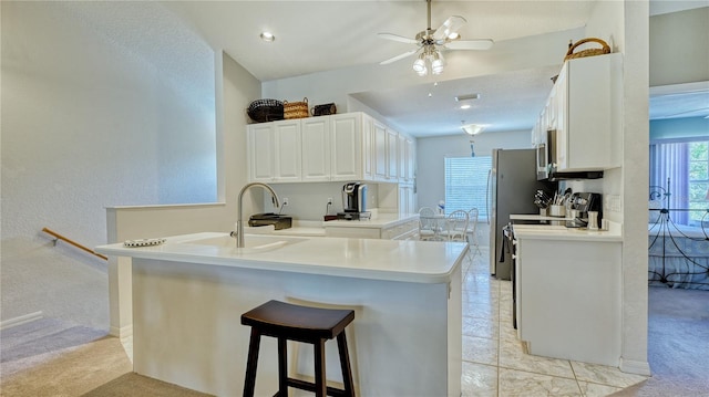 kitchen featuring white cabinetry, light carpet, kitchen peninsula, sink, and ceiling fan