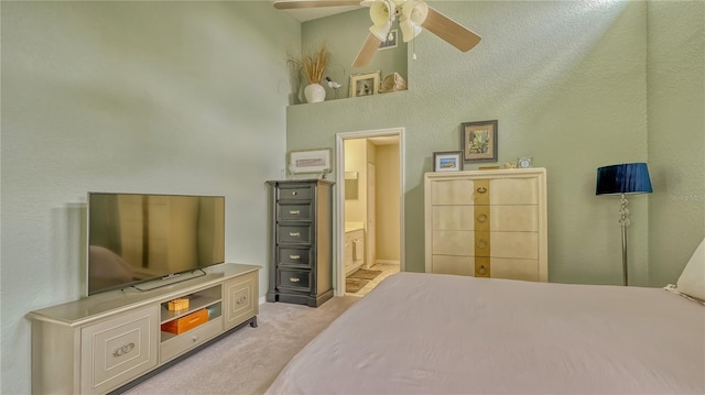 bedroom featuring light carpet, a high ceiling, ensuite bathroom, and ceiling fan