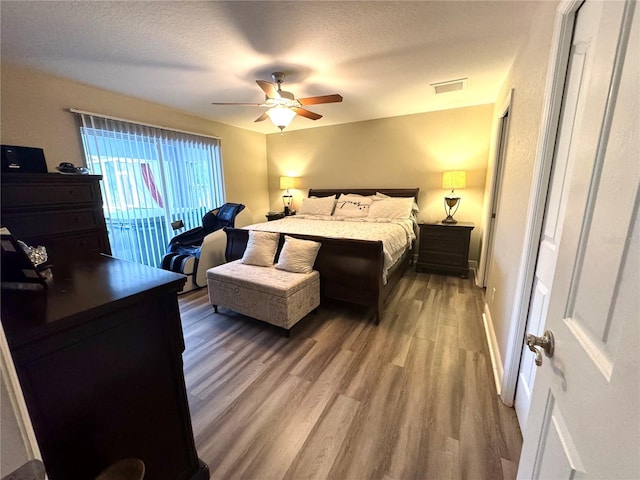 bedroom with a textured ceiling, access to exterior, ceiling fan, and hardwood / wood-style floors