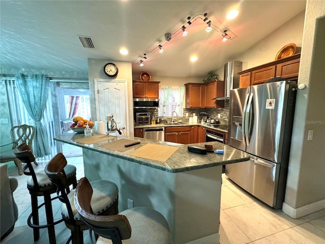 kitchen featuring appliances with stainless steel finishes, a healthy amount of sunlight, tasteful backsplash, and track lighting