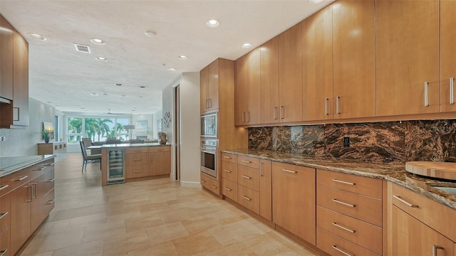 kitchen featuring decorative backsplash, stone counters, beverage cooler, and appliances with stainless steel finishes