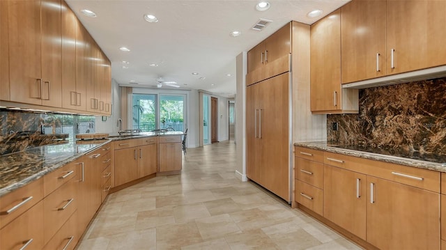 kitchen featuring stone countertops, sink, backsplash, ceiling fan, and black electric cooktop