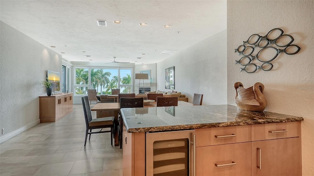 kitchen featuring wine cooler, ceiling fan, and dark stone countertops