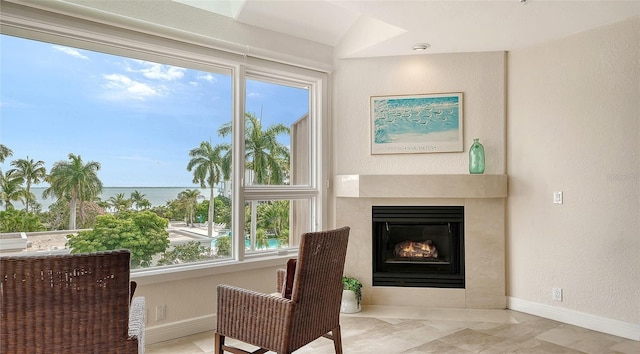 sitting room featuring a water view and lofted ceiling