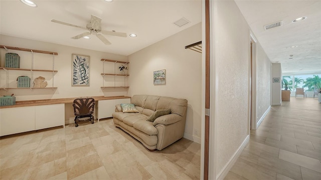 living room featuring ceiling fan and built in desk