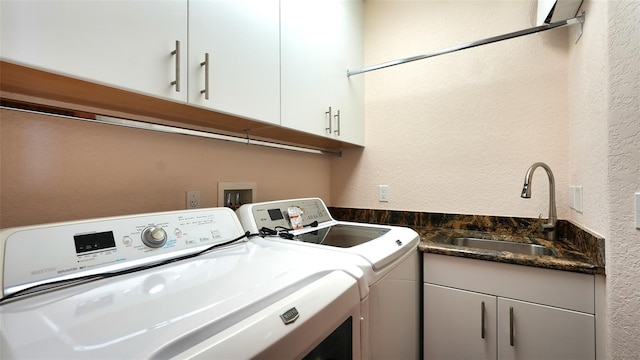 clothes washing area with cabinets, sink, and washing machine and clothes dryer